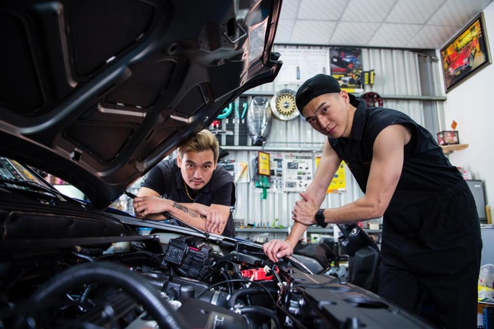 返鄉後，愛玩車的阿緯（右）和哥哥一起打理修車廠。