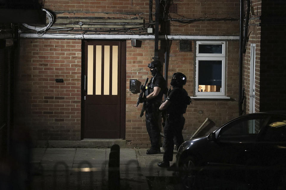 Armed police officers stand by a door at a block of flats off the Basingstoke Road in Reading after an incident at Forbury Gardens park in the town centre of Reading, England, Saturday, June 20, 2020. Several people were injured in a stabbing attack in the park on Saturday, and British media said police were treating it as “terrorism-related.” (Steve Parsons/PA via AP)