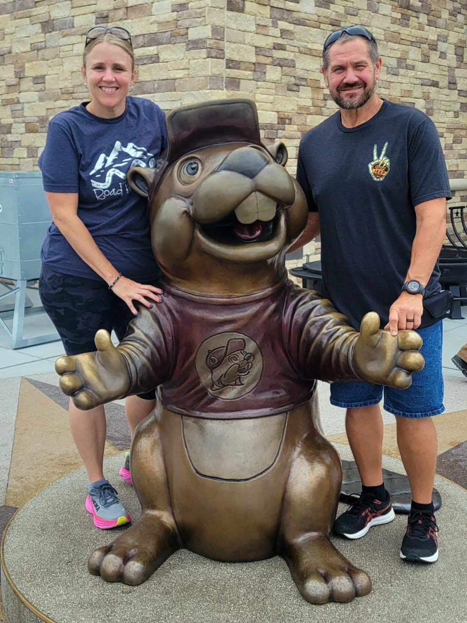 Jen Emig, left, and her husband Roger Emig pose for a photo with a Buc-ee's statue outside of the Buc-ee's travel center in Sevierville, Tennessee.