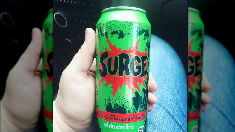 person holding can of surge