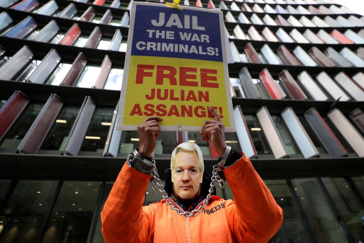 A demonstrator holds a banner and wears a Julian Assange mask opposite the Old Bailey: AP