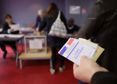 A person holds a voter's registration card before voting in the second round of 2017 French presidential election at a polling station in Paris, France, May 7, 2017. REUTERS/Eric Gaillard