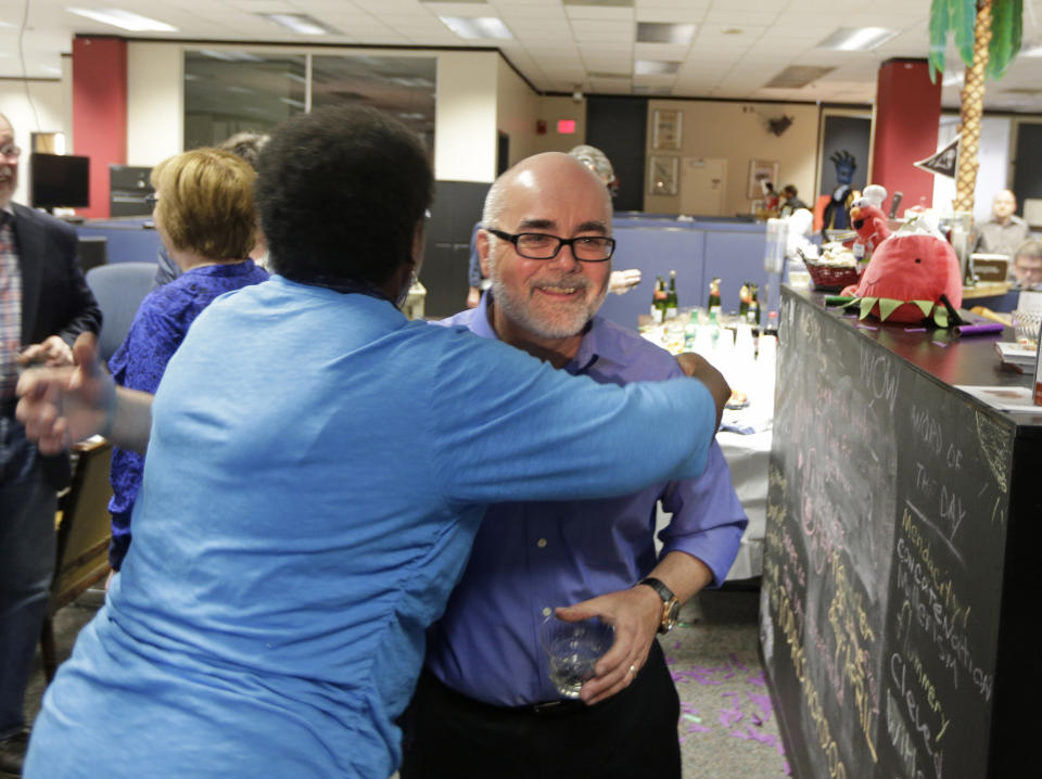 FILE - Charlotte Observer editorial cartoonist Kevin Siers, right, gets a hug from a co-worker as the newsroom as they celebrate Siers winning the Pulitzer Prize for Editorial Cartooning at the newspaper in Charlotte, N.C., on Monday, April 14, 2014. Siers was among three Pulitzer Prize-winning editorial cartoonists who were laid off last week. (AP Photo/Chuck Burton, File)