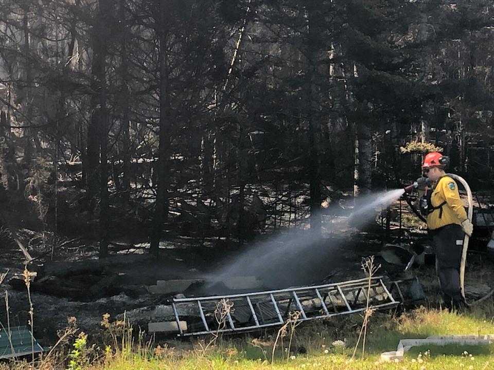 A firefighter helps douse hot spots with water on Tuesday afternoon at a property off of Highway 127, three kilometres from where the Stein Lake fire started. 