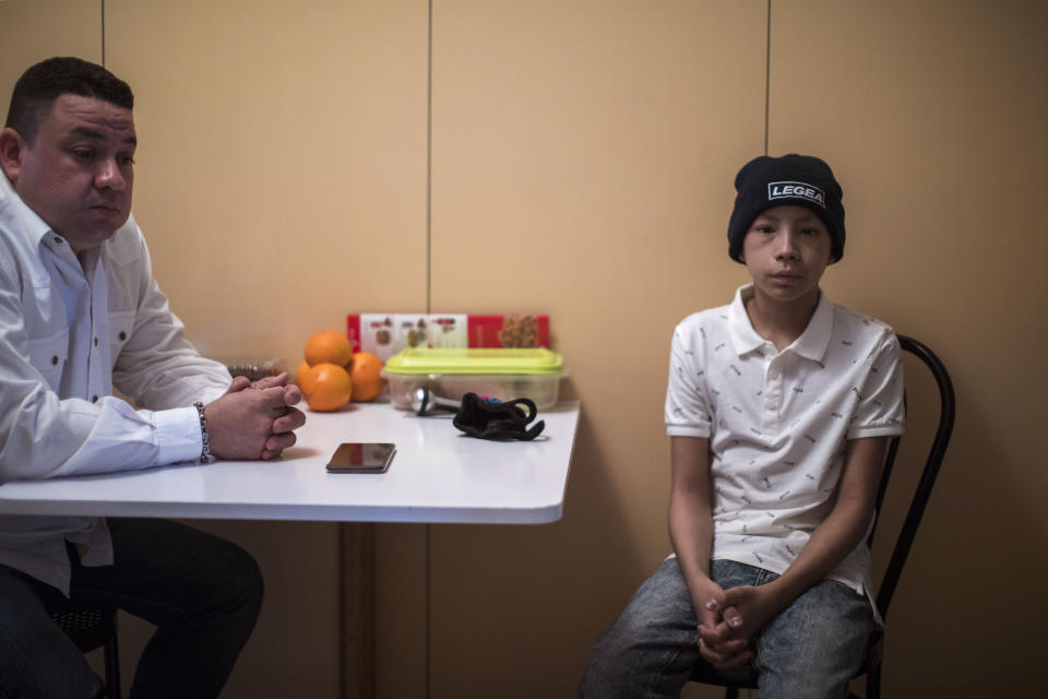 In this Thursday, Feb. 21, 2019 photo, Carlos Acosta and his son Jesus, sit at a hostel in Barcelona, Spain, where they have come for a bone marrow transplant and follow up care for the 12-year old child. The medical treatment for Jesus was to be paid for by Houston-based charity the "Simon Bolivar Foundation," but now his treatment along with treatment of at least eight other severely ill children, have became the unintended victims of U.S. sanctions. (AP Photo/Emilio Morenatti)