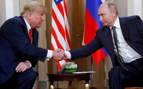 U.S. President Donald Trump and Russian President Vladimir Putin shake hands at the beginning of a meeting at the Presidential Palace in Helsinki, Finland last year - Credit: AP