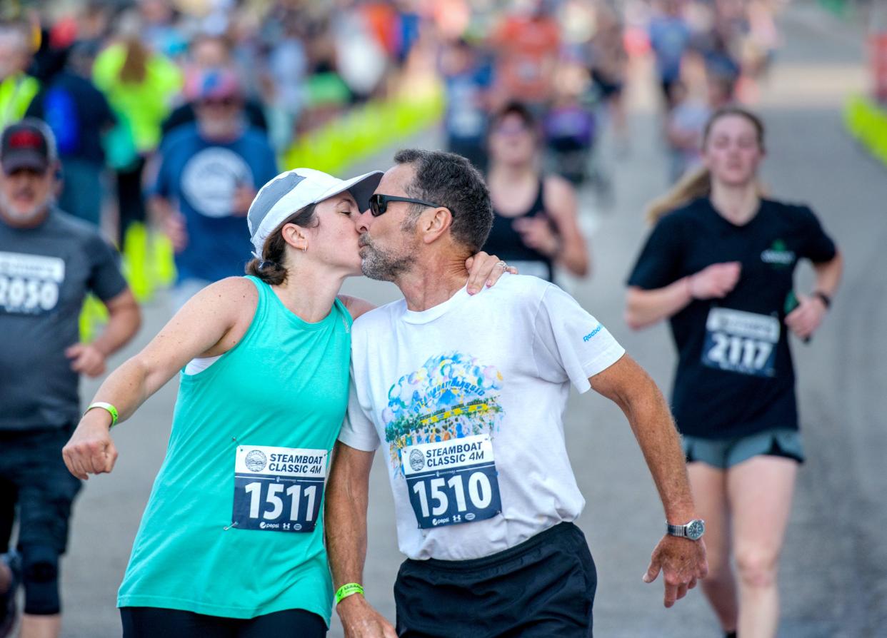 Adrienne Coleman (1511) of Mahomet and Ed Coleman of Canton share a kiss at the finish line of the Steamboat Classic 4-Mile race Saturday, June 17, 2023 in downtown Peoria.