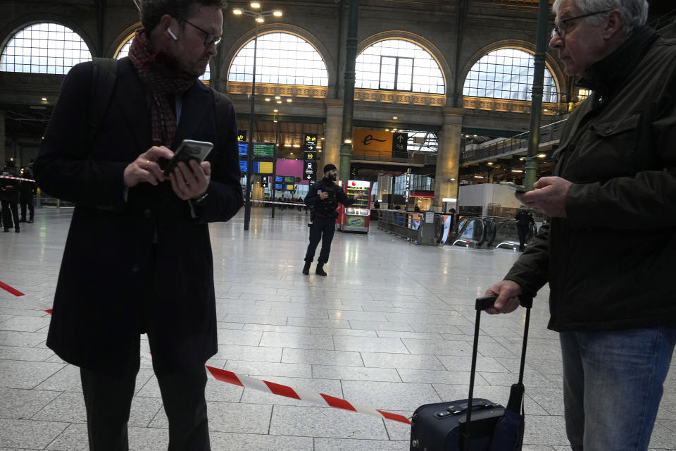 Travelers wait behind the police tape at the Gare du Nord train station, Wednesday, Jan. 11, 2023 in Paris. French media are reporting that people have been stabbed at a Paris train station and the interior minister says several people were injured before police "rapidly neutralized" the attacker. (AP Photo/Michel Euler)