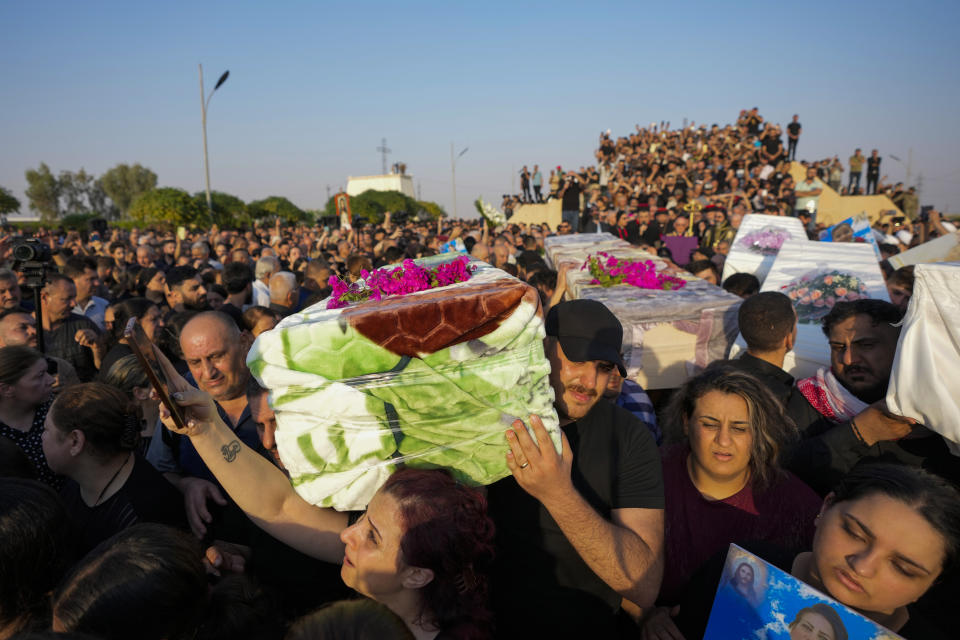 Friends and relatives attend the funeral of people who died in a fire during a wedding ceremony in Hamdaniya, Iraq, Wednesday, Oct. 27, 2023. A fire that raced through a hall hosting a Christian wedding in northern Iraq has killed around 100 people and injured 150 others, and authorities warn the death toll could rise. (AP Photo/Hadi Mizban