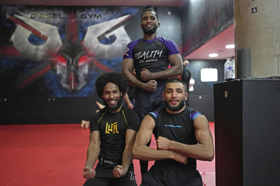 Flyweight MMA fighter Sabir Hussein, left, and MMA coach Warsame Ibrahim, top, pose for a photograph during a mixed martial arts practice session at Diesel Gym in the Docklands area of East London, Monday, March 25, 2024. The special sessions run by the nonprofit SCK Fitness are held at 10 p.m. during the Muslim holy month of Ramadan to accommodate dawn-to-dusk fasting. (AP Photo/Kin Cheung)