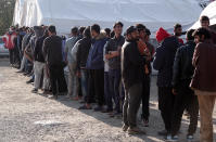 Migrants wait in line to receive supplies from the Red Cross at the Vucijak refugee camp outside Bihac, northwestern Bosnia, Monday, Oct. 21, 2019. Authorities in the town of Bihac on Monday stopped the delivery of water supplies to the Vucjak camp saying they want to draw attention to the problems in the camp set up on a former landfill and near mine fields from the 1992-95 war. (AP Photo/Eldar Emric)