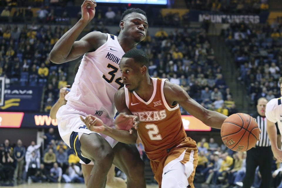 Texas guard Matt Coleman III (2) is defended by West Virginia forward Oscar Tshiebwe (34) as he goes to pass the ball during the first half of an NCAA college basketball game Monday, Jan. 20, 2020, in Morgantown, W.Va. (AP Photo/Kathleen Batten)