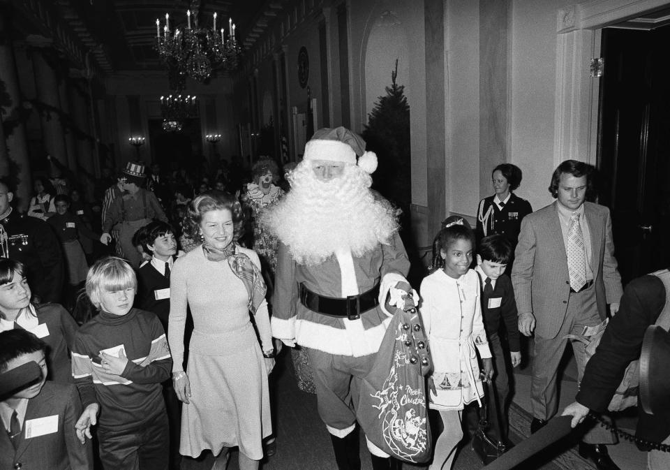First lady Betty Ford walks with Santa Claus and some of the children of diplomats at the White House on Tuesday, Dec. 17, 1975 prior to start of a party she hosted for the youngsters. In addition to Saint Nicholas the children were treated to clowns and puppet show. (AP Photo/PHX)