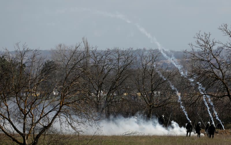 Greek riot police officers stand guard as tear gas is being fired near Turkey's Pazarkule border crossing, in Kastanies