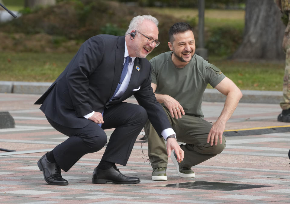 Ukrainian President Volodymyr Zelenskyy, right, and Latvian President Egils Levits smile at the "Walk of the Brave" in Kyiv, Ukraine, Friday, Sept. 9, 2022.The "Walk of the Brave" name plates mark those who have helped in the struggle against the Russian invasion of Ukraine. (AP Photo/Efrem Lukatsky)