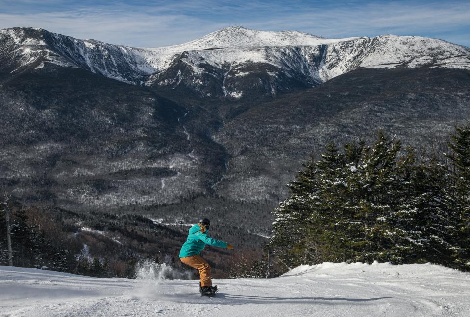 A snowboarder descnets Wildcat with a full view of Mount Washington.