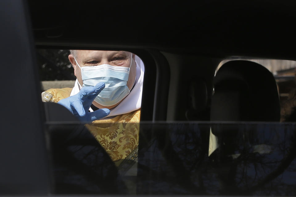 Rev. William Schipper, pastor of Mary, Queen of the Rosary Parish, left, wears a mask and gloves out of concern for the coronavirus as he speaks with a parishioner in the parking lot of the church, on Easter Sunday, April 12, 2020, in Spencer, Mass. Schipper sprinkled holy water and blessed people who remained in their vehicles as they drove through the parking lot of the church. (AP Photo/Steven Senne)