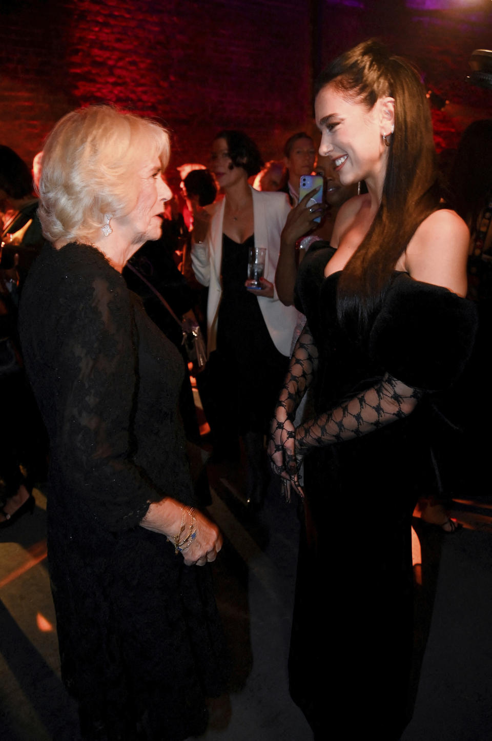 Britain's Camilla, Queen Consort, talks with Dua Lipa, right, during the Booker Prize at the Roundhouse in London, Monday Oct. 17, 2022. (Toby Melville/Pool via AP)