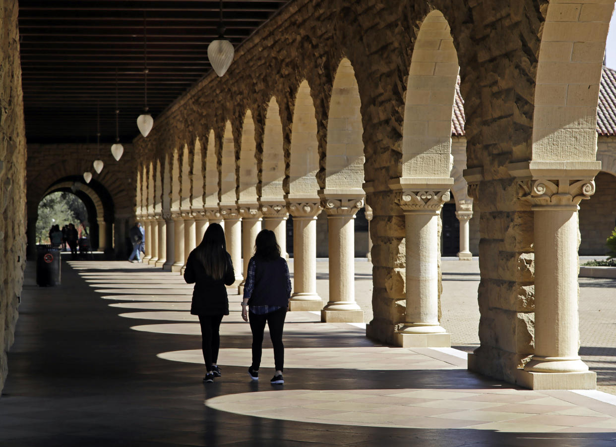 FILE — Students walk on the Stanford University campus in Stanford, Calif, March 14, 2019. When students at Stanford University return to campus in January 2022, they'll be barred from holding parties or other big gatherings for two weeks. (AP Photo/Ben Margot, File)