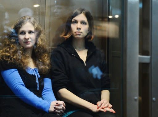 Two jailed members of the all-girl punk band "Pussy Riot: Maria Alyokhina (left) and Nadezhda Tolokonnikova sit in a glass-walled cage in a court in Moscow. German Chancellor Angela Merkel has clashed with Russian President Vladimir Putin over the jailing of feminist rock band Pussy Riot in a meeting aimed at soothing tensions over human rights