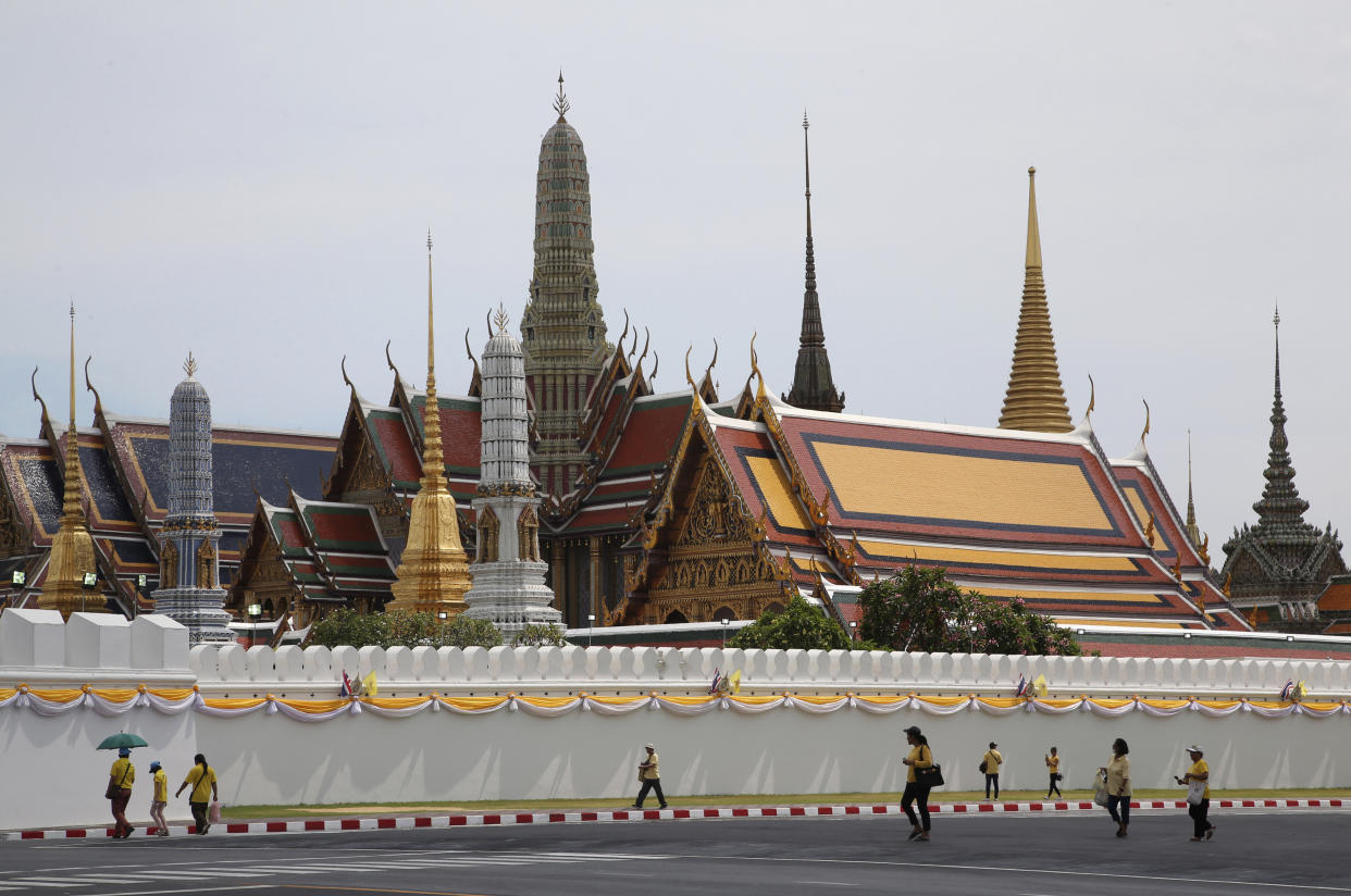 Thai people wearing the color of the king, yellow, to honor their King Maha Vajiralongkorn walk outside Grand Palace in Bangkok, Thailand, Saturday, May 4, 2019. Saturday began three days of elaborate centuries-old ceremonies for the formal coronation of Vajiralongkorn, who has been on the throne for more than two years following the death of his father, King Bhumibol Adulyadej, who died in October 2016 after seven decades on the throne. (AP Photo/Sakchai Lalit)