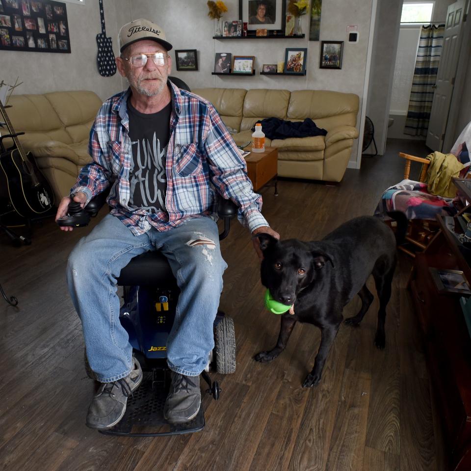 Army veteran Kenneth Clelland of Carleton is pictured in his mobile home with the wheelchair that was loaned to him by Binson’s Medical Equipment & Supplies in Macomb County. The paraplegic veteran lives in Carleton with Shelby, a 4-year-old black Labrador and shepherd mix, and a cat named Ally.