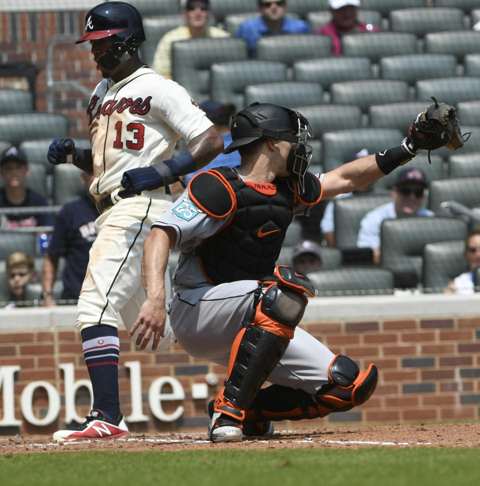 Atlanta Braves' Ronald Acuna Jr. (13) scores on a sacrifice fly to left field by Freddie Freeman as Miami Marlins catcher J.T. Realmuto reaches for the throw during the fifth inning of the first game in a baseball doubleheader Monday, Aug. 13, 2018, in Atlanta. (AP Photo/John Amis)