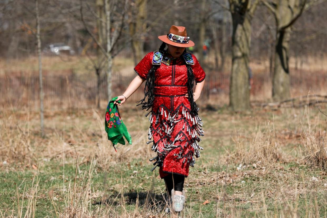 An Indigenous jingle dress dancer participates in a ceremony at a prescribed burn at High Park in Toronto on April 13, 2023.  (Heather Waldron/CBC - image credit)