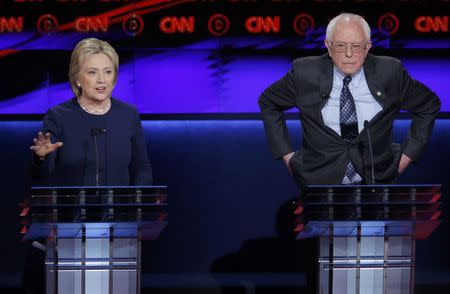 Democratic U.S. presidential candidate Hillary Clinton speaks as rival Bernie Sanders listens during the Democratic U.S. presidential candidates' debate in Flint, Michigan, March 6, 2016. REUTERS/Jim Young