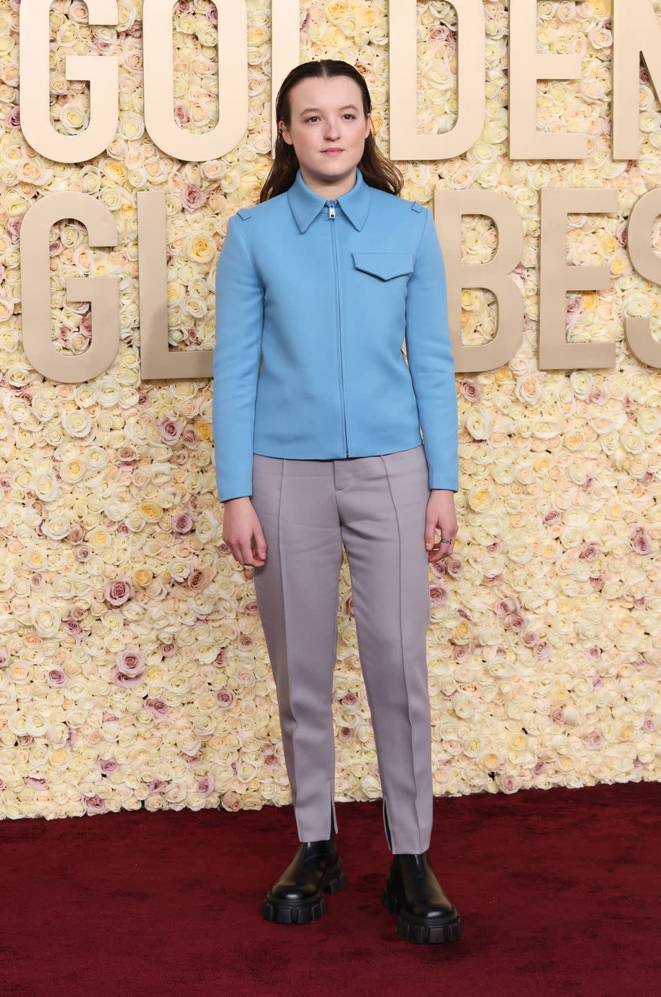 bella ramsey standing in front of a flower wall at the golden globes 2024