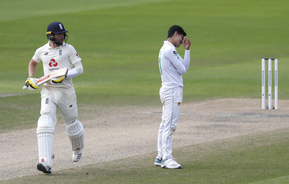 Pakistan's Naseem Shah, right, reacts as England's Chris Woakes, left, runs between the wickets to score during the fourth day of the first cricket Test match between England and Pakistan at Old Trafford in Manchester, England, Saturday, Aug. 8, 2020. (Lee Smith/Pool via AP)