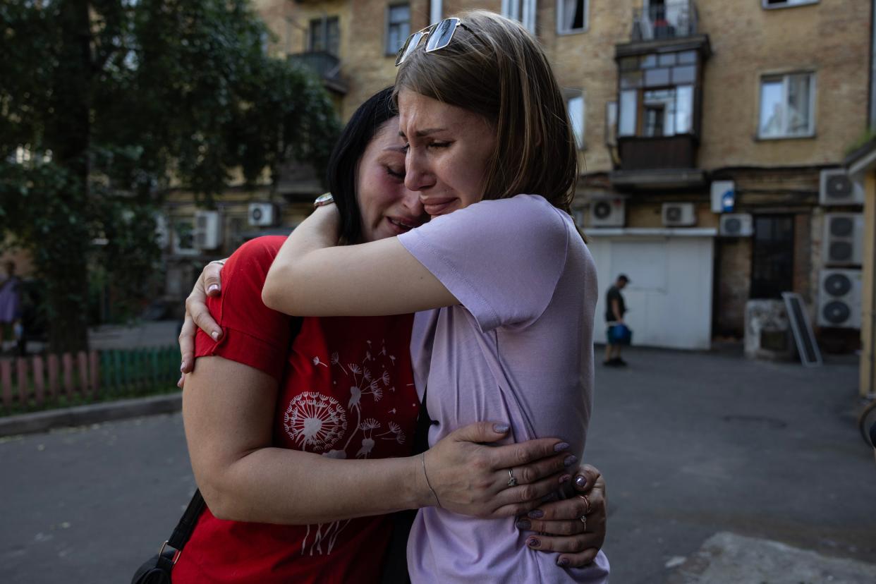 Workers from the Vertel cafe hug as they start to clean up after a missile attack (Getty Images)