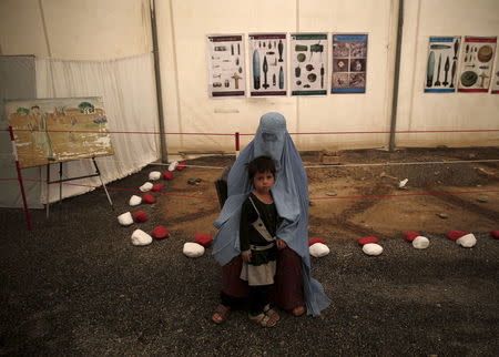 An Afghan refugee woman, clad in a burqa, sits with her child after arriving at a United Nations High Commissioner for Refugees (UNHCR) registration centre in Kabul, Afghanistan August 26, 2015. REUTERS/Ahmad Masood