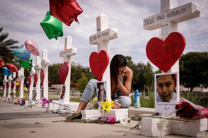 <p>A woman writes a note on a cross for Eric Ivan Ortiz-Rivera at a memorial with wooden crosses for each of the 49 victims of the Pulse Nightclub, next to the Orlando Regional Medical Center, June 17, 2016 in Orlando, Florida. (Drew Angerer/Getty Images) </p>