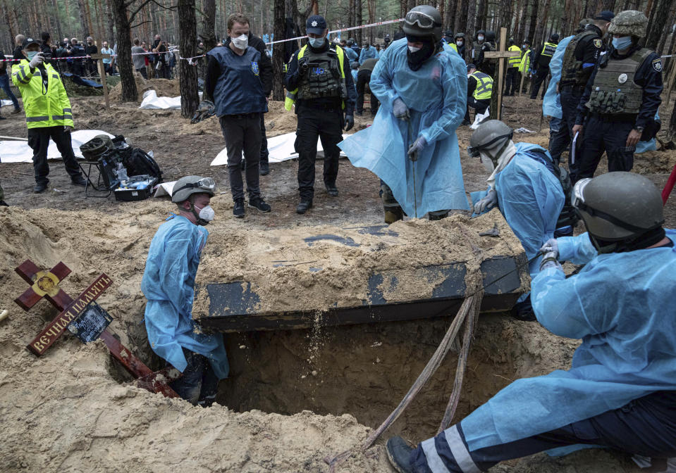 Emergency workers move a body during the exhumation in the recently retaken area of Izium, Ukraine, Friday, Sept. 16, 2022. Ukrainian authorities discovered a mass burial site near the recaptured city of Izium that contained hundreds of graves. It was not clear who was buried in many of the plots or how all of them died, though witnesses and a Ukrainian investigator said some were shot and others were killed by artillery fire, mines or airstrikes. (AP Photo/Evgeniy Maloletka)