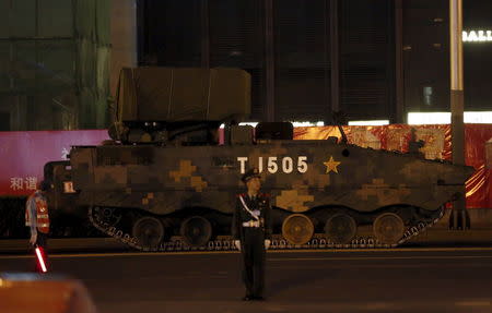 A paramilitary policeman stands guard in front of an armored vehicle which is parked for the upcoming military parade to mark the 70th Anniversary of the end of World War Two, in Beijing, China, September 2, 2015. REUTERS/Kim Kyung-Hoon