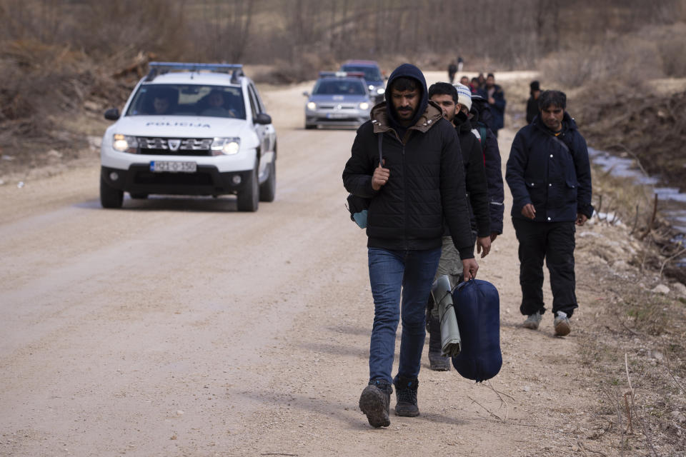 FILE - Police vehicles drive past a group of migrants moving towards Croatian border in Lipa near Bihac, Western Bosnia, on April 21, 2021. An independent investigative group on Thursday April 6, 2023 accused Croatian officials and police of using a clandestine WhatsApp group to share sensitive information about migrants trying to enter the country. (AP Photo/Darko Bandic, File)