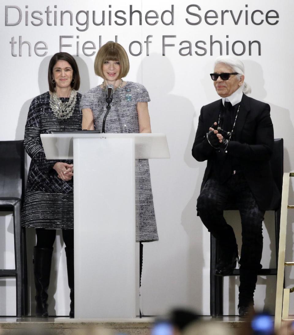 Anna Wintour, at podium, editor-in-chief of Vogue makes an introduction speech honoring Chanel designer Karl Lagerfeld, right, as and Karen Katz, left, president and CEO of Neiman Marcus, watches during an ceremony at the department store where Lagerfeld was presented with a fashion award, Wednesday, Dec. 11, 2013, in Dallas. (AP Photo/Tony Gutierrez)