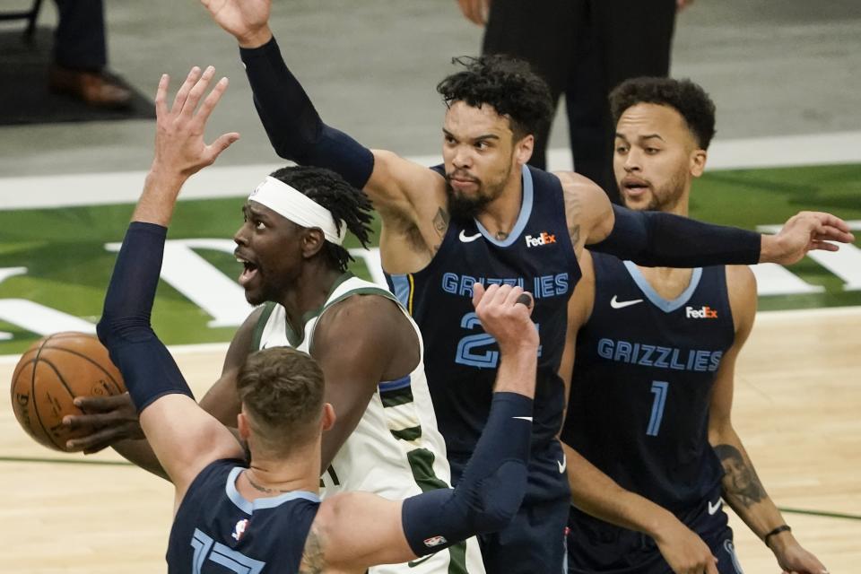 Milwaukee Bucks' Jrue Holiday shoots past Memphis Grizzlies' Jonas Valanciunas and Dillon Brooks during the first half of an NBA basketball game Saturday, April 17, 2021, in Milwaukee. (AP Photo/Morry Gash)