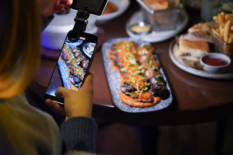 Content creator Jensen Savannah produces a client video at El Puro Cuban Restaurant, Thursday, March 14, 2024, in Charlotte, N.C. (AP Photo/Erik Verduzco)