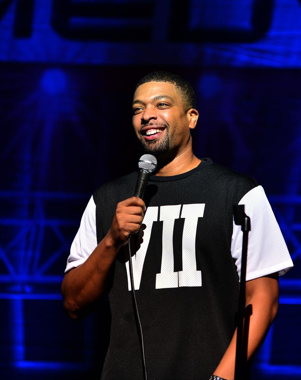 DeRay Davis smiles onstage during a stand-up set