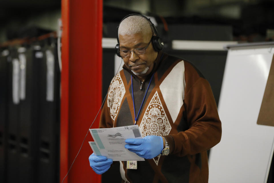 Armstead Jones, Sr., election director with the Baltimore City Board Elections, holds two ballots in question during a teleconference with the election board at a canvasing warehouse ahead of the 7th Congressional District special election, Monday, April 27, 2020, in Baltimore. Democrat Kweisi Mfume and Republican Kimberly Klacik won special primaries for the Maryland congressional seat that was held by the late Elijah Cummings. Voters have been encouraged to mail in their ballots and only three in-person polling centers have been set up across the district in an effort to contain the spread of the new coronavirus. (AP Photo/Julio Cortez)