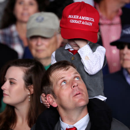 A father looks up at his child as supporters rally with U.S. President Donald Trump at Middle Georgia Regional Airport in Macon, Georgia, U.S. November 4, 2018. REUTERS/Jonathan Ernst