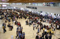 Hundreds of airline passengers gather to check their flights at the Ninoy Aquino International Airport after a Chinese Xiamen Air Boeing passenger plane skidded off the runway while landing Friday, Aug. 17, 2018, in Manila, Philippines. The Xiamen Air flight MF8667 has skidded off a runway at Manila's airport while landing in a downpour and its 157 passengers and eight crew members have been evacuated by emergency slide. (AP Photo/Bullit Marquez)