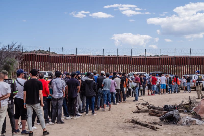 Asylum seekers stand in a line while volunteers hand out food, water, blankets, hats and clothes near the border wall in Jacumba, Calif., on May 13, 2023. File Photo by Ariana Dreshler/UPI
