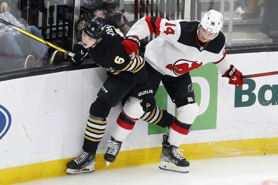 New Jersey Devils' Nathan Bastian (14) checks Boston Bruins' Mason Lohrei (6) during the first period of an NHL hockey game Saturday, Dec. 30, 2023, in Boston. (AP Photo/Michael Dwyer)