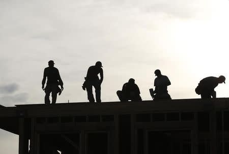 Workers are silhouetted as they stand on the roof of a building under construction in Los Angeles December 2, 2010. REUTERS/Mario Anzuon