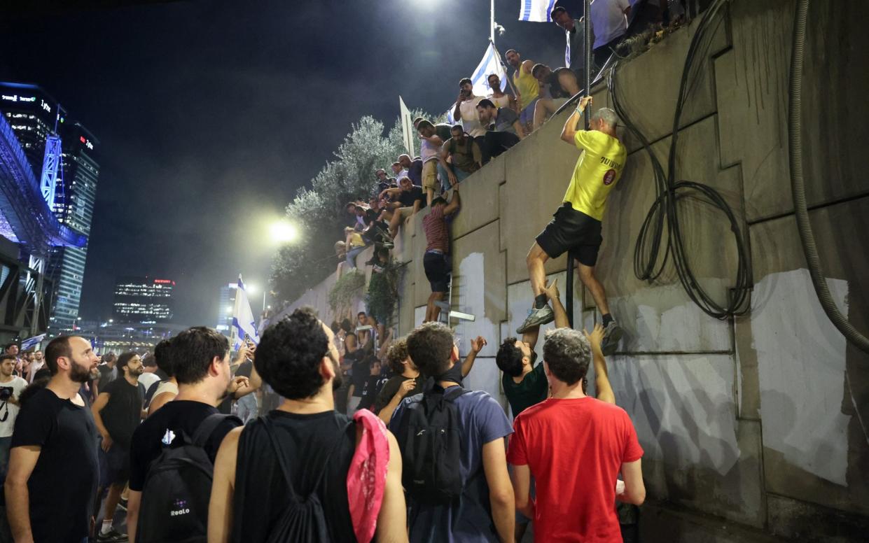 Protesters climb down a wall during an anti-government rally