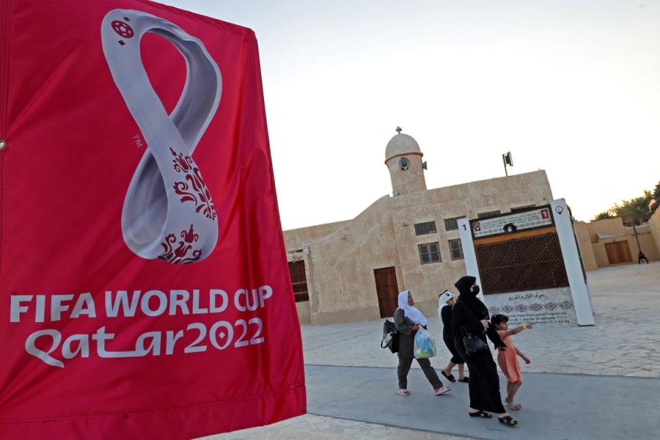 People walk past Fifa World Cup banners at a beach in Doha (AFP via Getty Images)