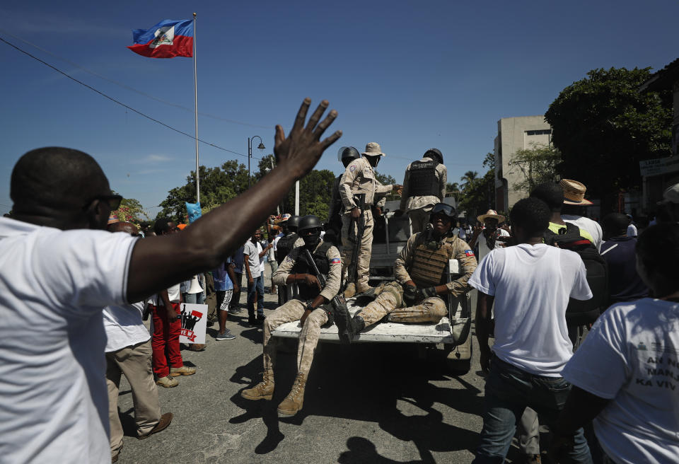 Police patrol amid protesters demanding the resignation of Haitian President Jovenel Moise during a march led by the art community in Port-au-Prince, Haiti, Sunday, Oct. 13, 2019. Protests have paralyzed the country for nearly a month, shuttering businesses and schools. (AP Photo/Rebecca Blackwell)